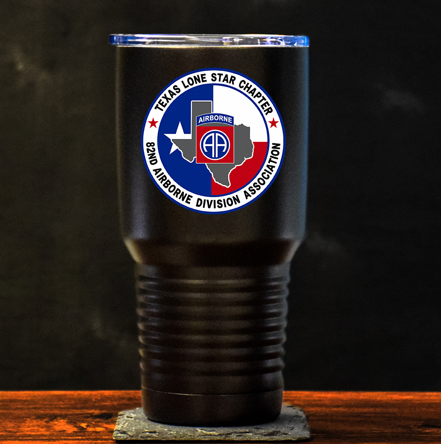 A black insulated 30oz tumbler with a clear lid sits on a wooden surface against a dark background. The tumbler features a circular Texas Lone Star Chapter 82nd Airborne Division Association logo on the front.
